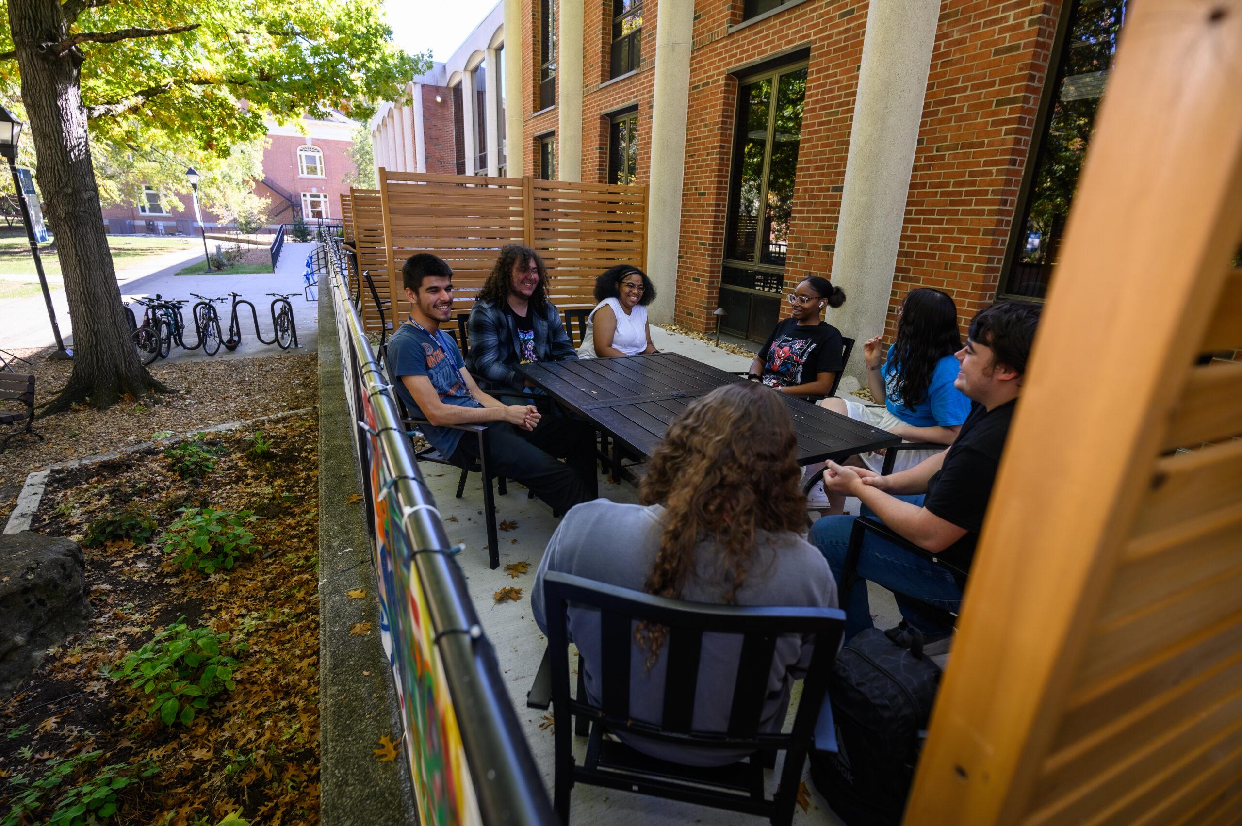Students are shown sitting around a table at the outdoor study area outside of Hutchins Library.